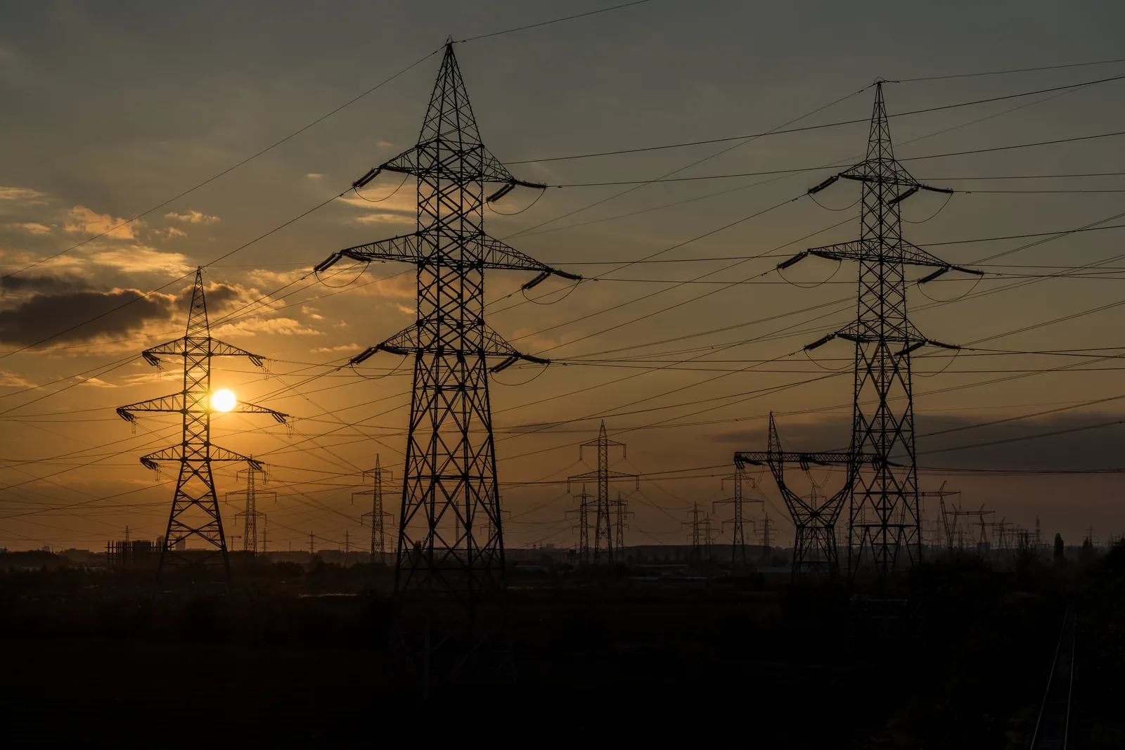 Torres eléctricas al atardecer con el sol cerca del horizonte
